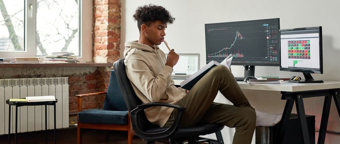 Investor researching stocks at their desk and computer.