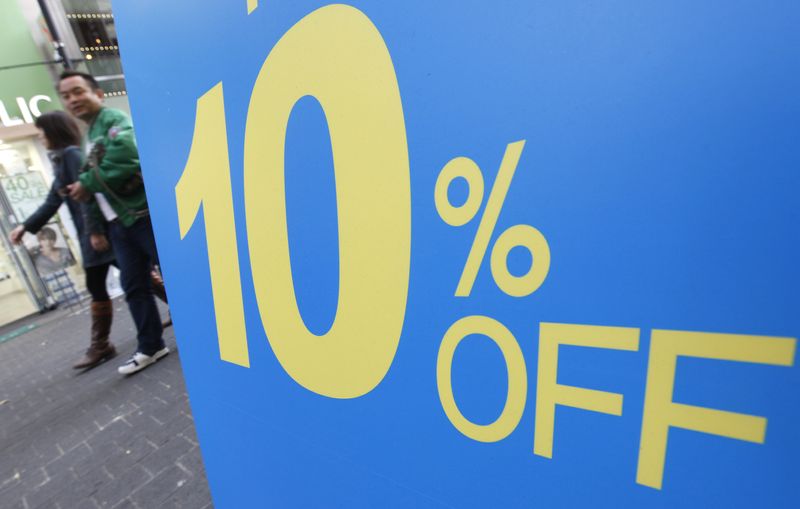 Shoppers walk past a discount sign of a shoe shop at Myeongdong shopping district in Seoul