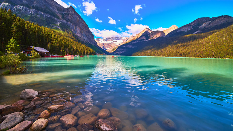 Lake Louise, with turquoise water and rocky shore surrounded by mountain peaks and forests, Banff National Park, Canada