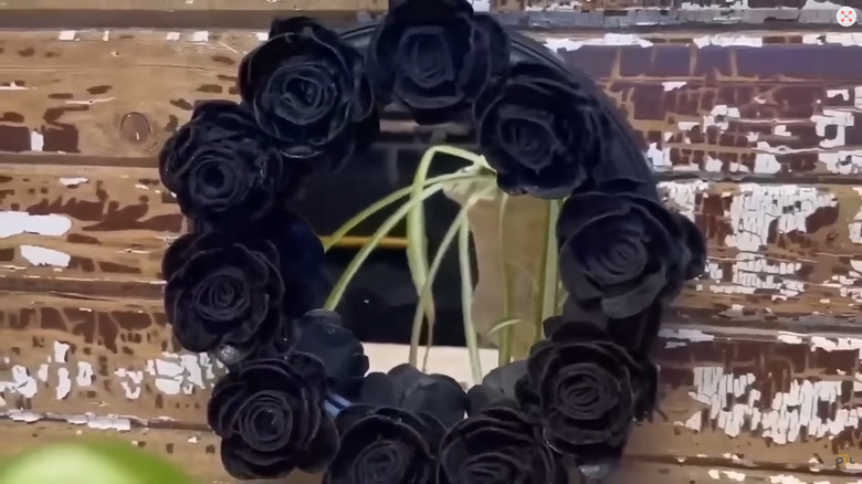 Mirror with the frame covered in black flowers made from egg cartons