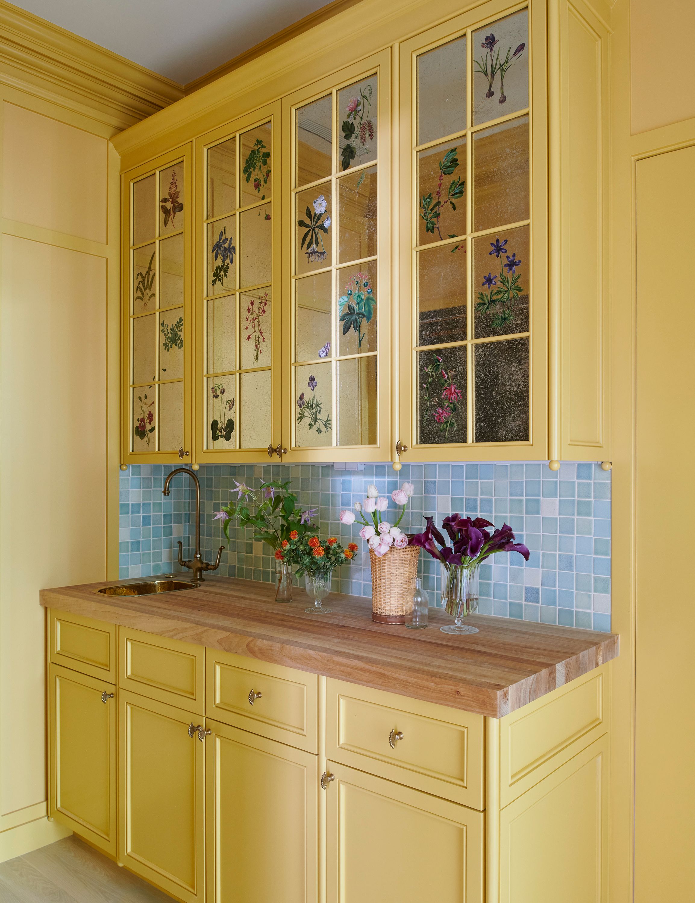In the egg yolk–hued butler’s pantry Kemble had Miriam Ellner Design paint églomisé flowers on the glass of the cabinet doors. The faucet is by PE Guerin.