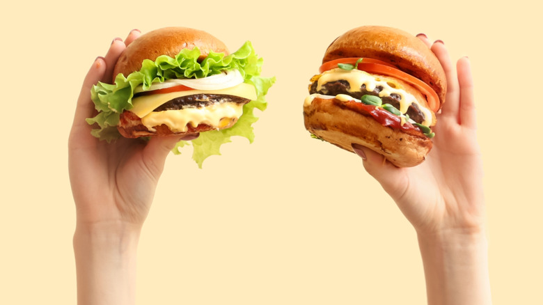 Two hands holding burgers