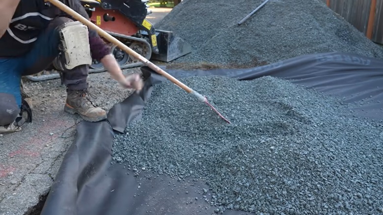 Person spreading crushed stone to build a gravel driveway