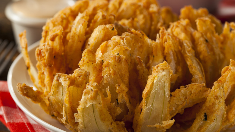 Outback's bloomin' onion on a white plate with some sauce in the background