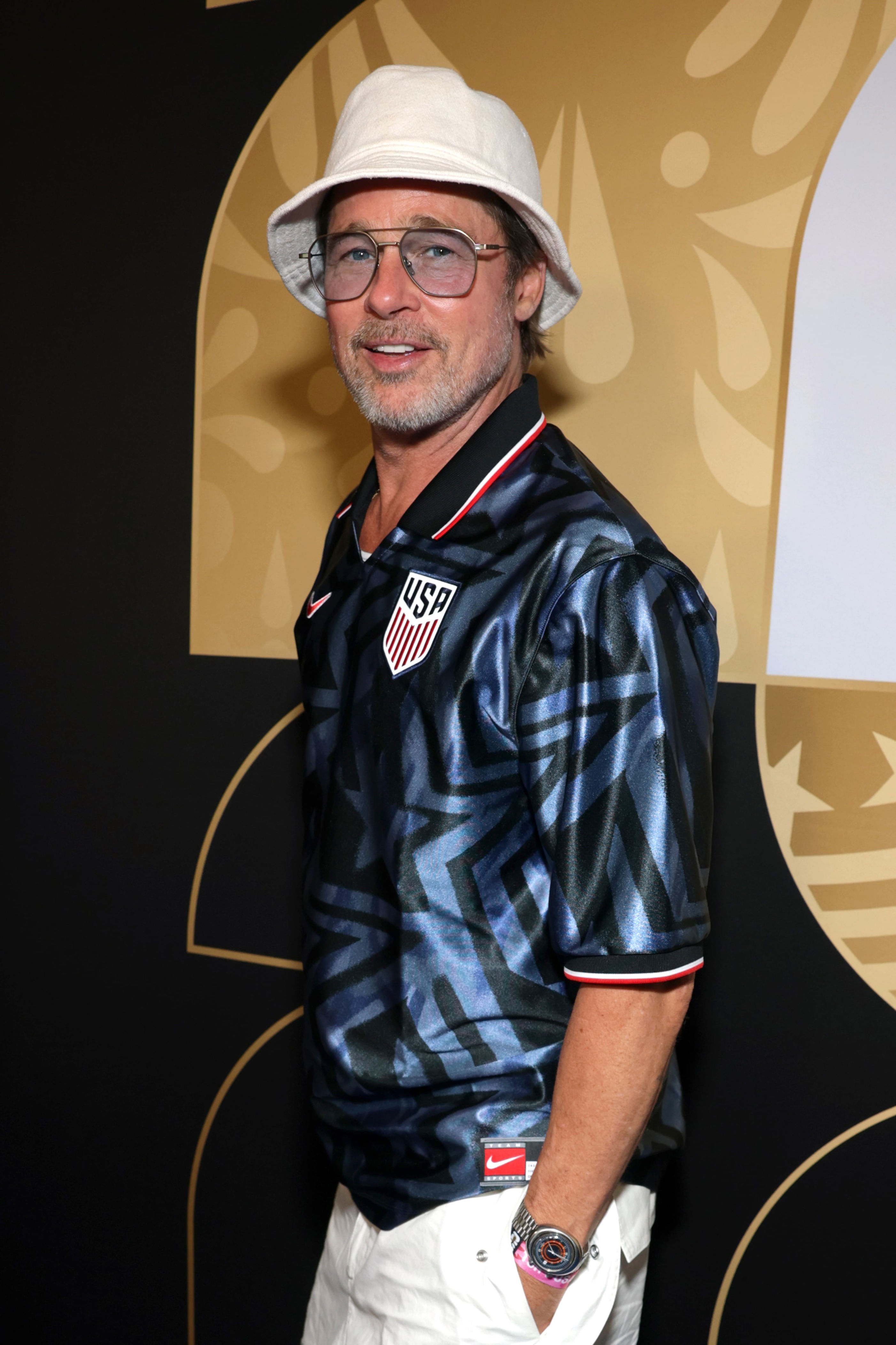 Brad Pitt attends the FIFA World Cup 2026 Group D match between Türkiye and the USA wearing a white bucket hat and aviator glasses in 2026. / Matt Winkelmeyer - FIFA/FIFA / Getty Images