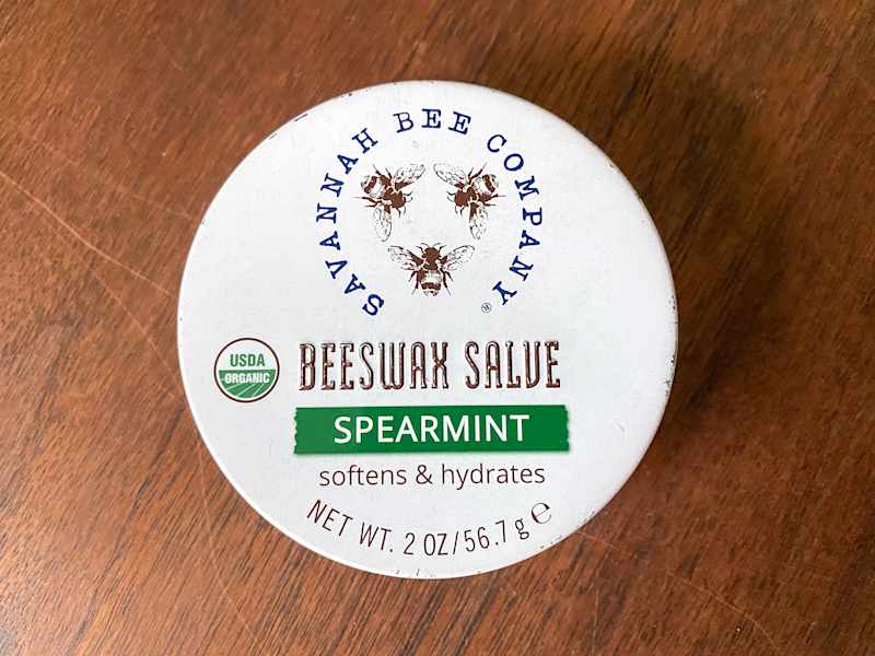 Container of Savannah Bee Company Beeswax Salve in Spearmint, labeled as USDA Organic, on a wooden surface.