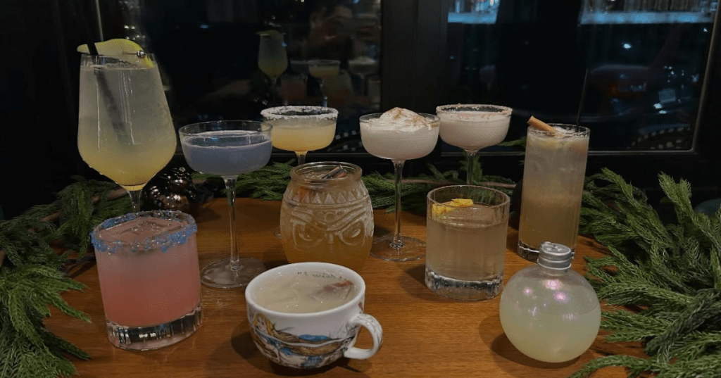An array of cocktails sit on a table surrounded by evergreen branches at The Rabbit Hole restaurant in Conshohocken, Pennsylvania.