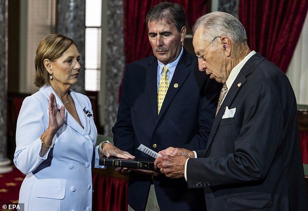 Nordone (L) is sworn in on July 14 by Senator Chuck Grassley (R) as her husband Larry (C) looks on