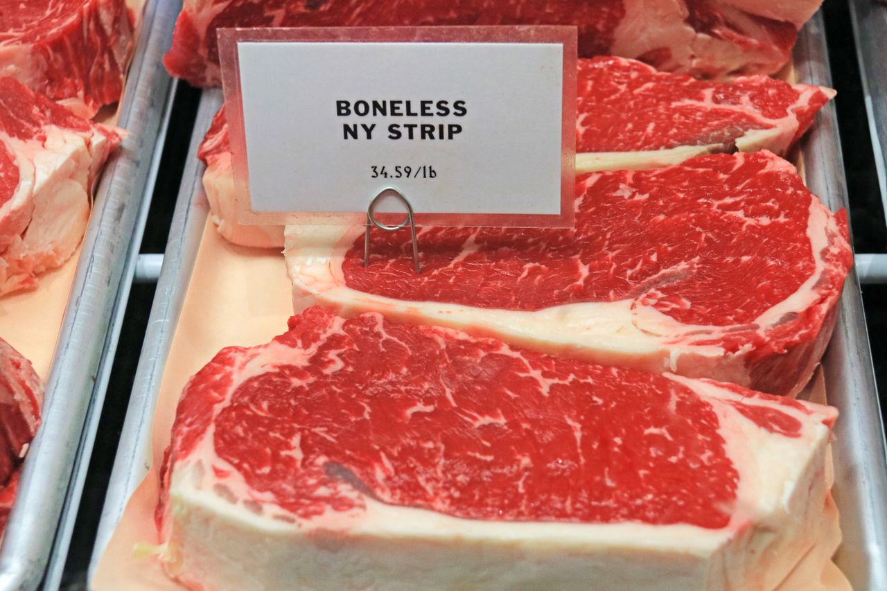 Boneless NY Strip steaks displayed with a price sign