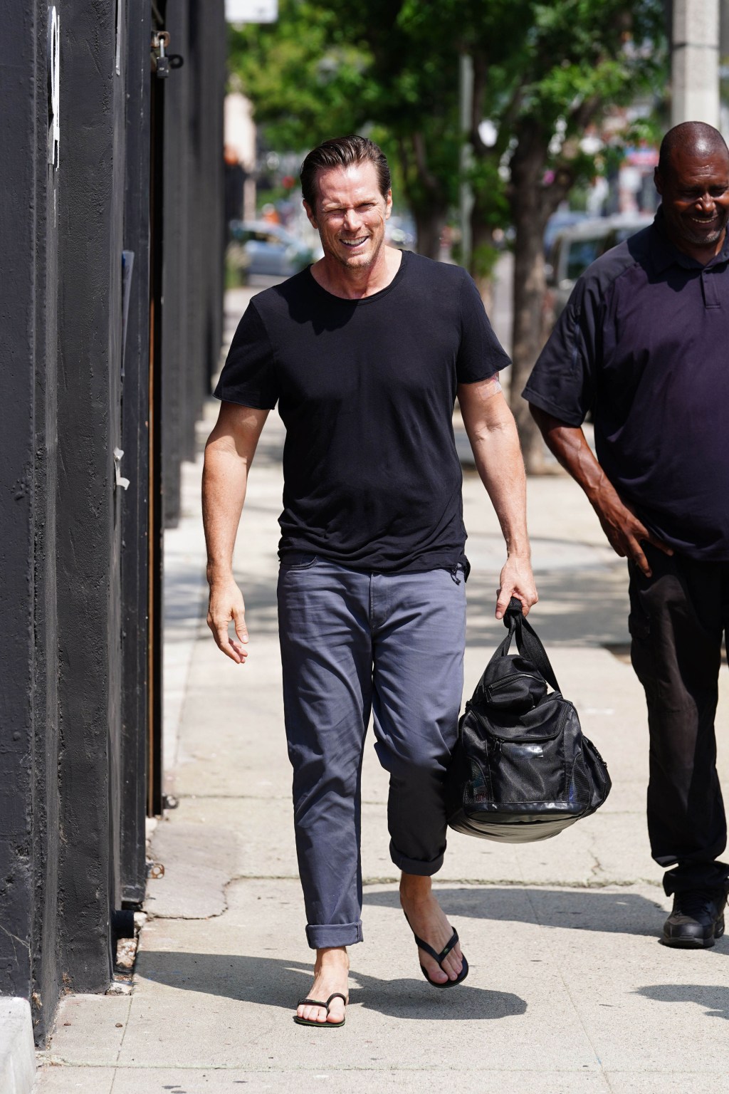 Jason Lewis walking on a sidewalk.