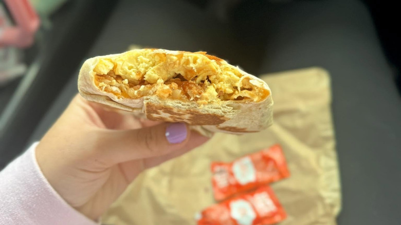 A hand holds a breakfast crunchwrap from Taco Bell.