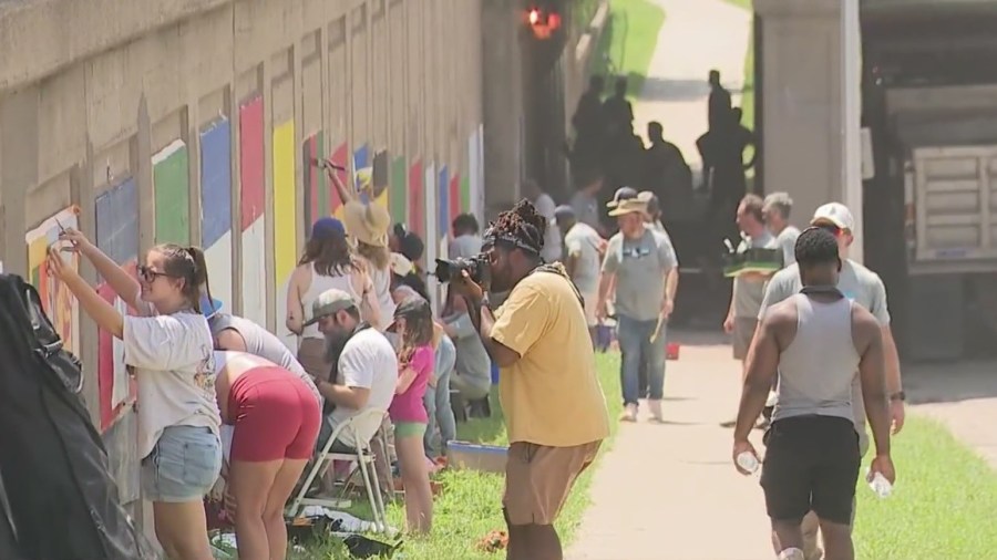 Volunteers brave heat to restore historic northeast flag mural
