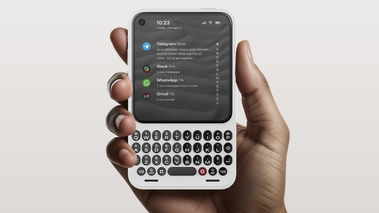Person holding the white Clicks Communicator smartphone with the message hub displayed on the screen.