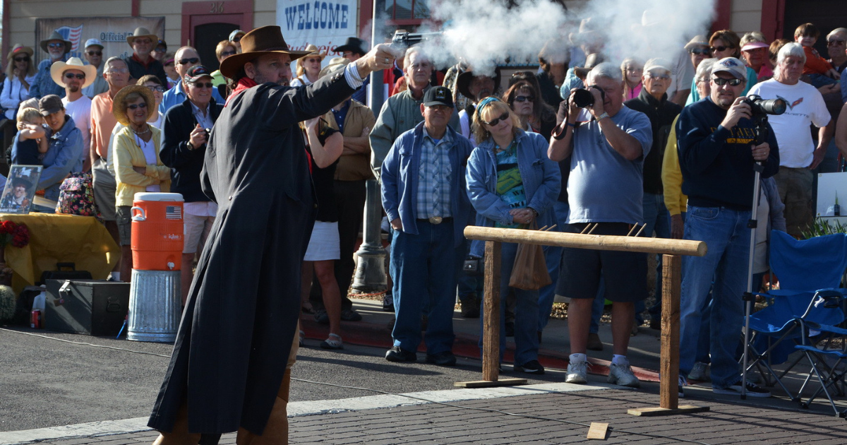 A cowboy reenactor fires a blank pistol during an Old West gunfight performance at Gold Rush Days in Wickenburg, Arizona.