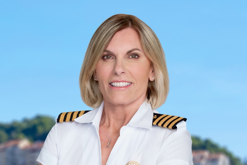 Captain Sandy Yawn wearing her yachting uniform in front of a hillside.