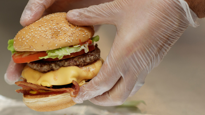 Gloved hands holding a Five Guys hamburger