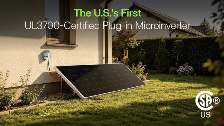 Photo of a cream-colored stucco home's backyard with a solar panel plugged into an exterior outlet.