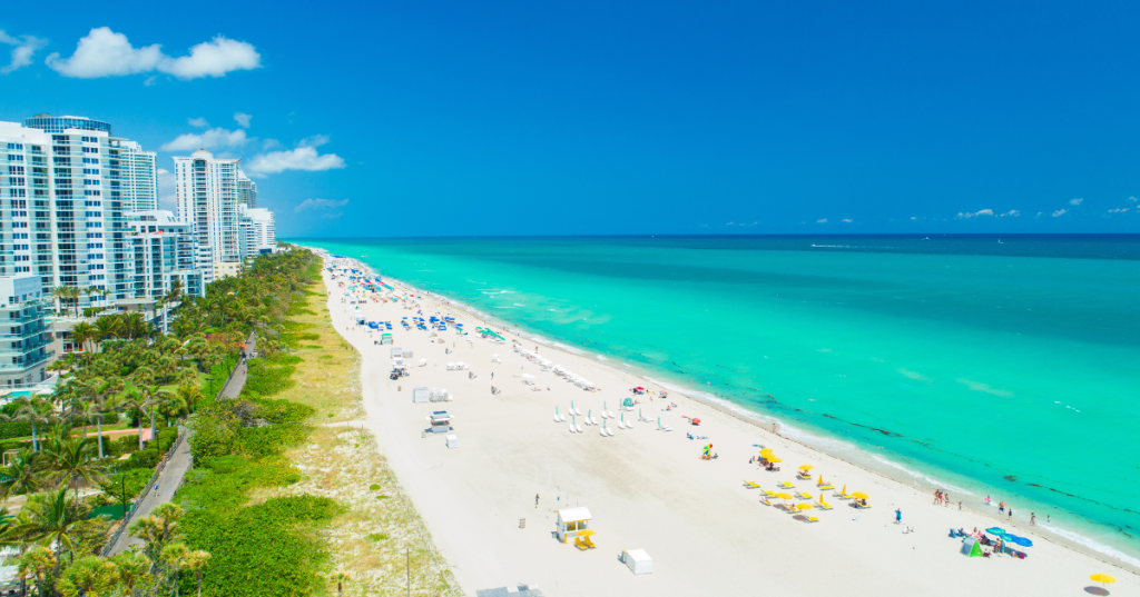White sandy beach in Florida with bright teal water and high-rise buildings