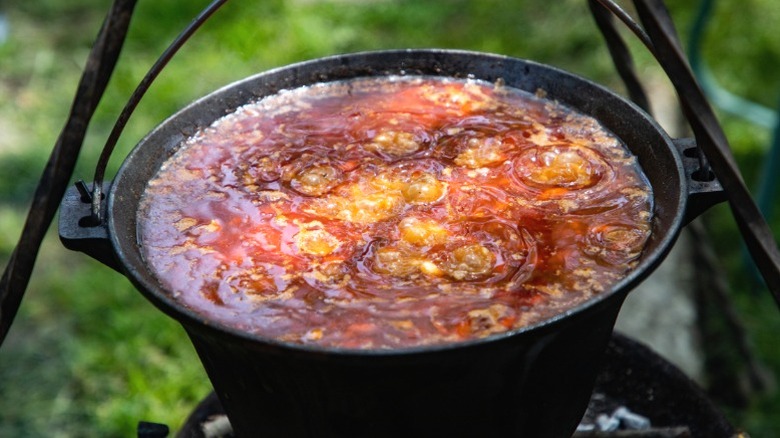 Pot of chili cooking over a campfire