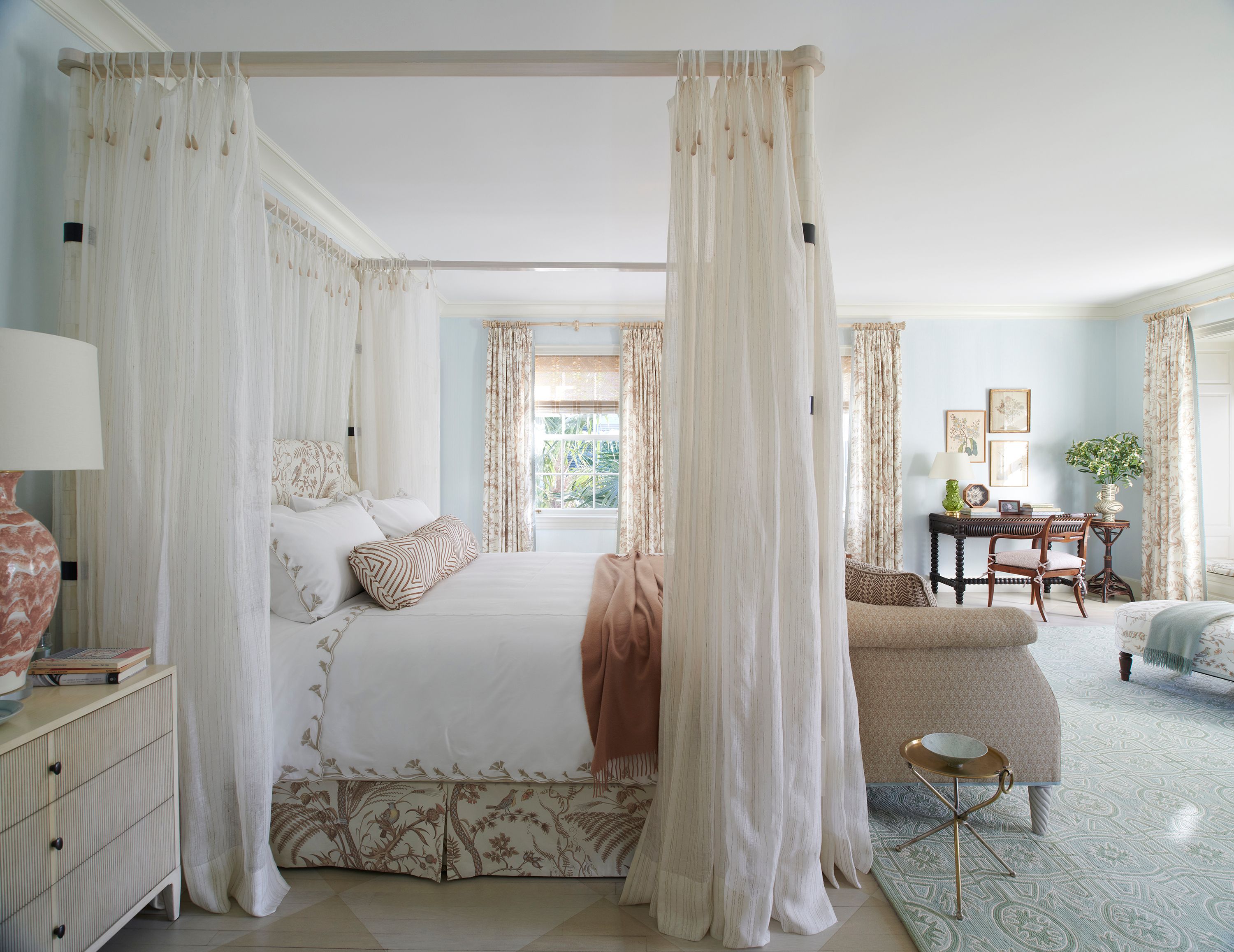 The primary bedroom is the calmest resting place in the house with sky blue walls only shades away from the white ceiling. The inlaid-bone four-poster bed is custom by Kemble Interiors. The nightstands are by Sherrill Furniture and the bedding by Pioneer Linen and Matouk. The Wedgwood-hued New England Collection rug provides a more classical foil for the Brunschwig & Fils curtains.