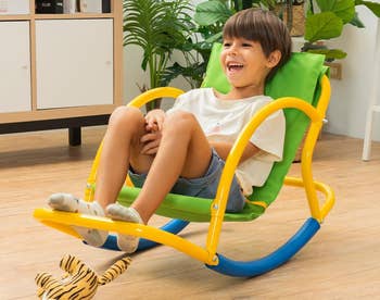 Child enjoying a colorful indoor chair seesaw, advertised as