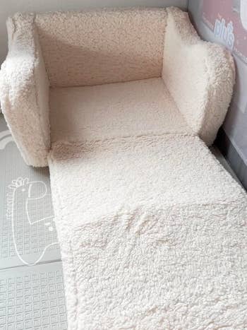 Sherpa-covered armchair with an extended matching foot cushion, suitable for cozy home decor
