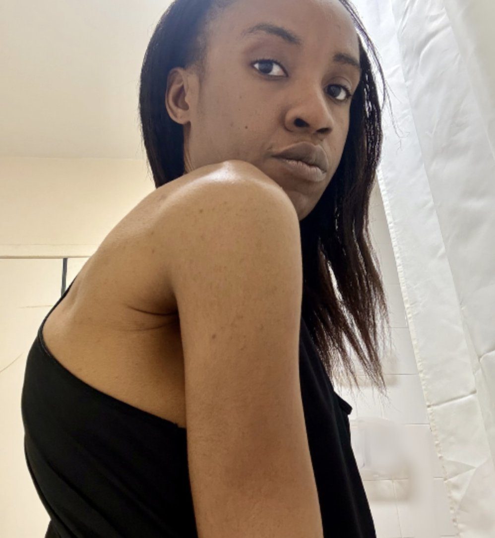 Side view of Erica in her bathroom, looking at the camera over one shoulder
