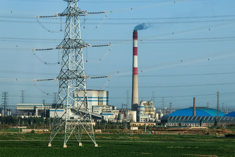 A view of a coal-fired power plant and a pylon of high-voltage power line surrounded by fields, in Baotou