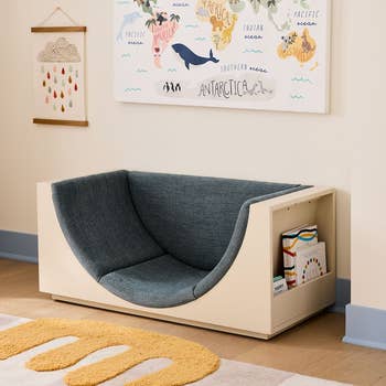 Children's reading nook with a comfortable cushioned seat and built-in bookshelf. A world map decorates the wall above. Ideal for kids' spaces