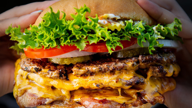Hands holding a fully loaded cheeseburger from Kopp's Frozen Custard in Wisconsin