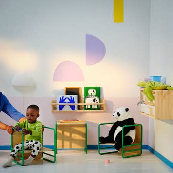 Child playing with a toy in a stylish kids' room with wall art and stuffed animals