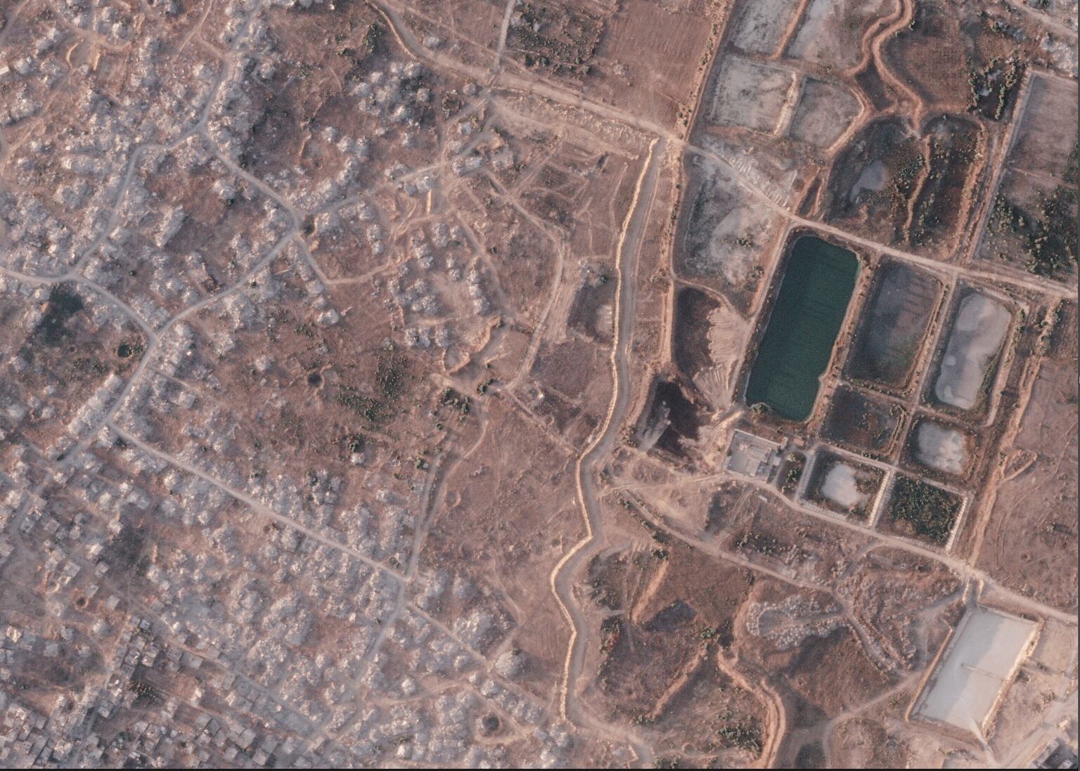 A section of an earth barrier being built by the Israeli military. To the left is the demolished town of Beit Lahia and to the right a defunct sewage treatment plant (Planet Labs PBC/AP)