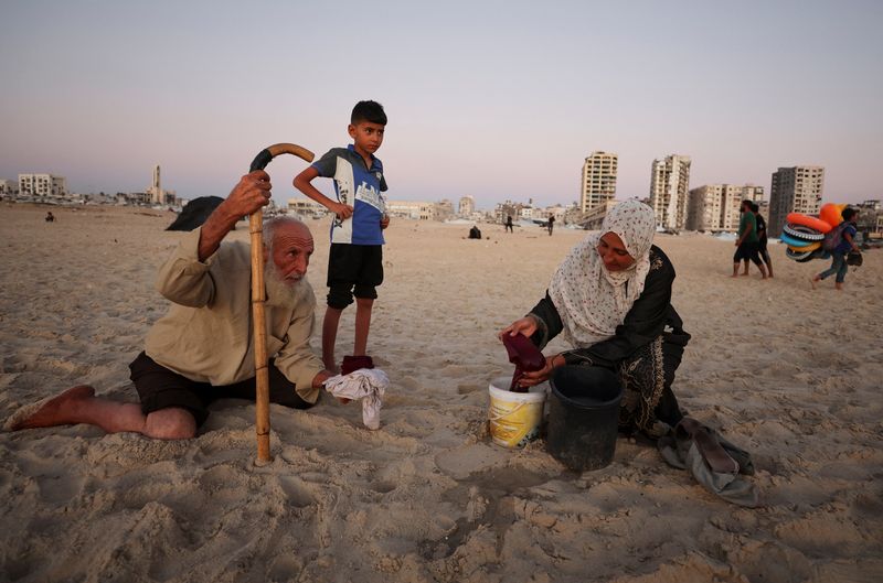 Displaced Palestinian woman washes clothes on the shore of the Mediterranean Sea, in Gaza