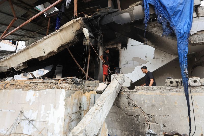 Palestinians inspect the site of an Israeli strike on a house in Gaza City