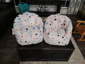 Two patterned bean bag chairs placed on a dark coffee table in a cozy living room setting