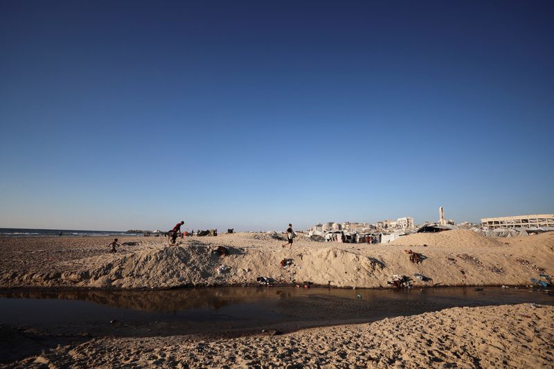 Wastewater flows next to tents sheltering displaced Palestinians, in Gaza