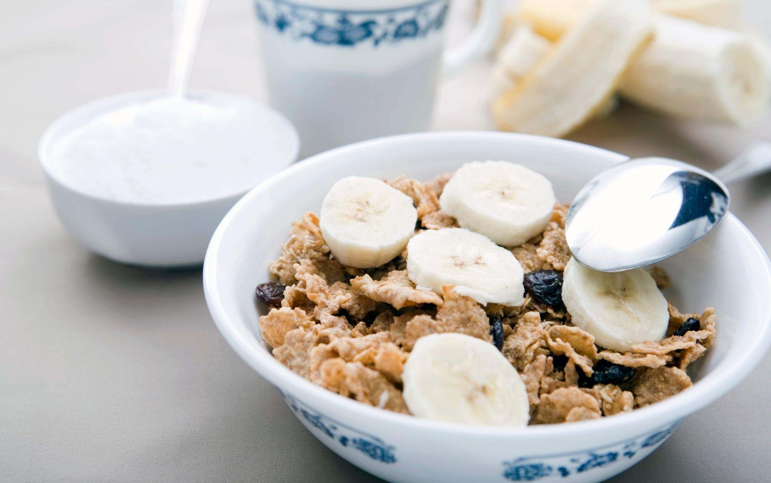 A bowl of bran flakes with bananas and raisins