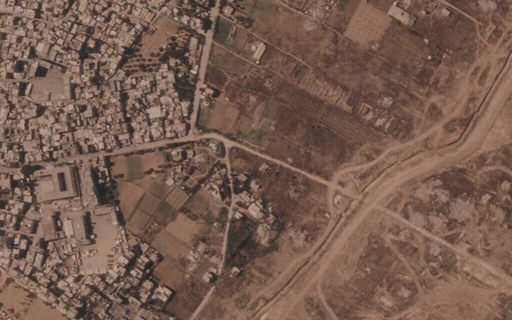 This satellite image from Planet Labs PBC shows a section of an earthen barrier being built by the Israeli military, right side of image moving top to bottom, in the central Gaza Strip, July 1, 2026. At left is the Maghazi camp, and on the other side are homes demolished by the military. (Planet Labs PBC via AP)