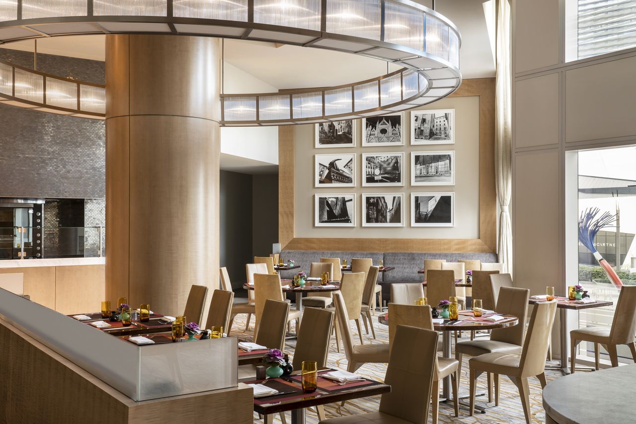A dining area with tables and chairs decorative lights above and framed photographs on the wall