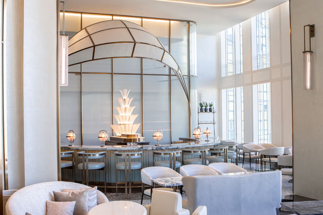 A stylish bar area with intricate lighting and seating arrangements featuring a decorative central fixture located in a luxury hotel setting
