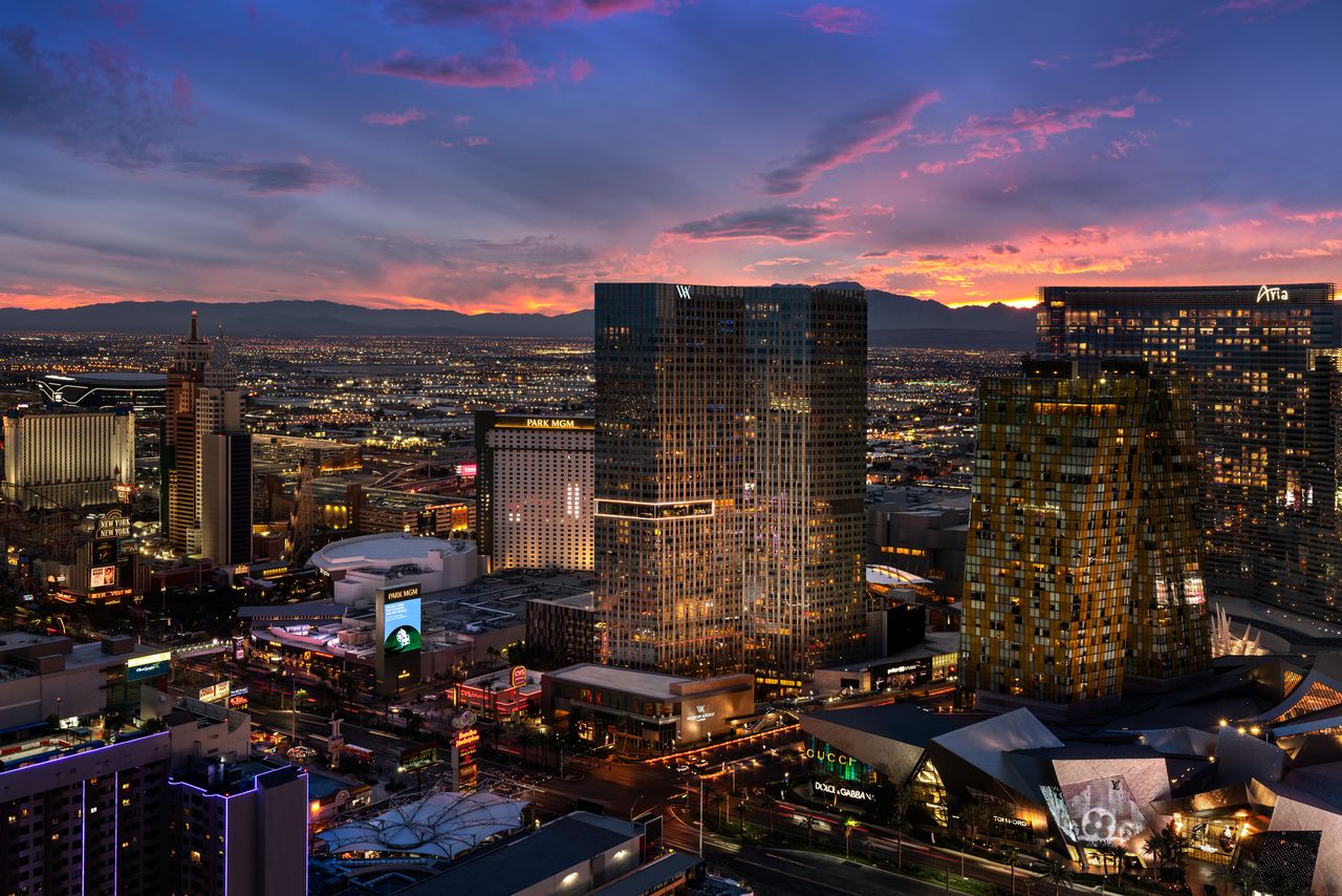 Skyline view of a city at sunset featuring a prominent modern hotel building amid urban structures