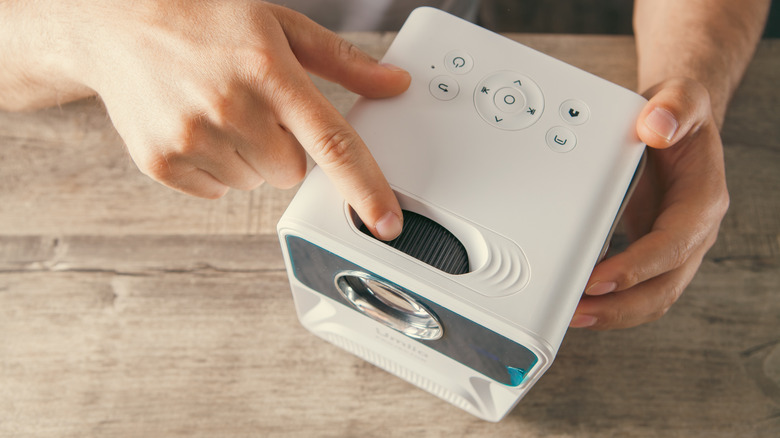 A man examines a small projector.