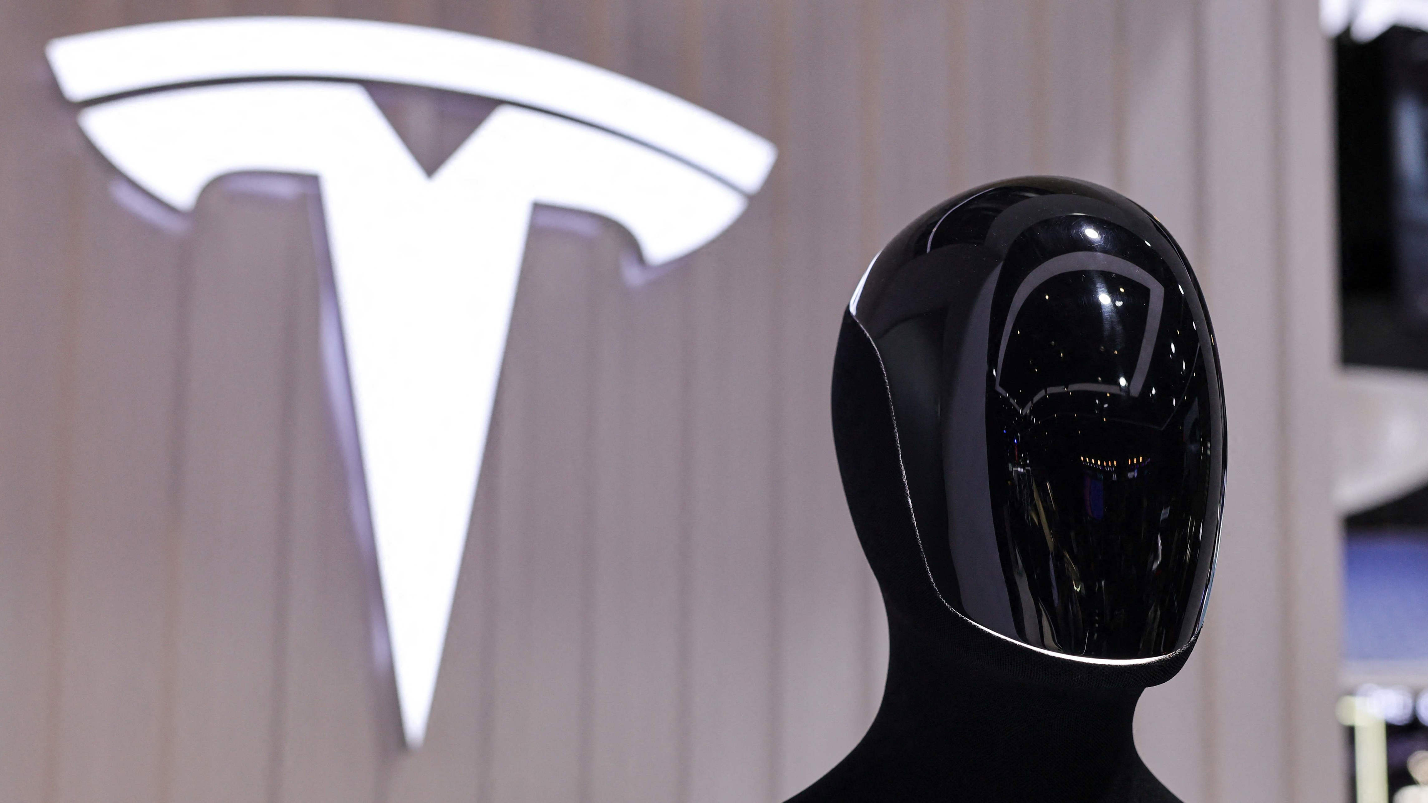 A Tesla Optimus robot is displayed next to a logo at the company's booth at the 8th China International Import Expo (CIIE) in Shanghai, China, November 6, 2025.REUTERS/Maxim Shemetov