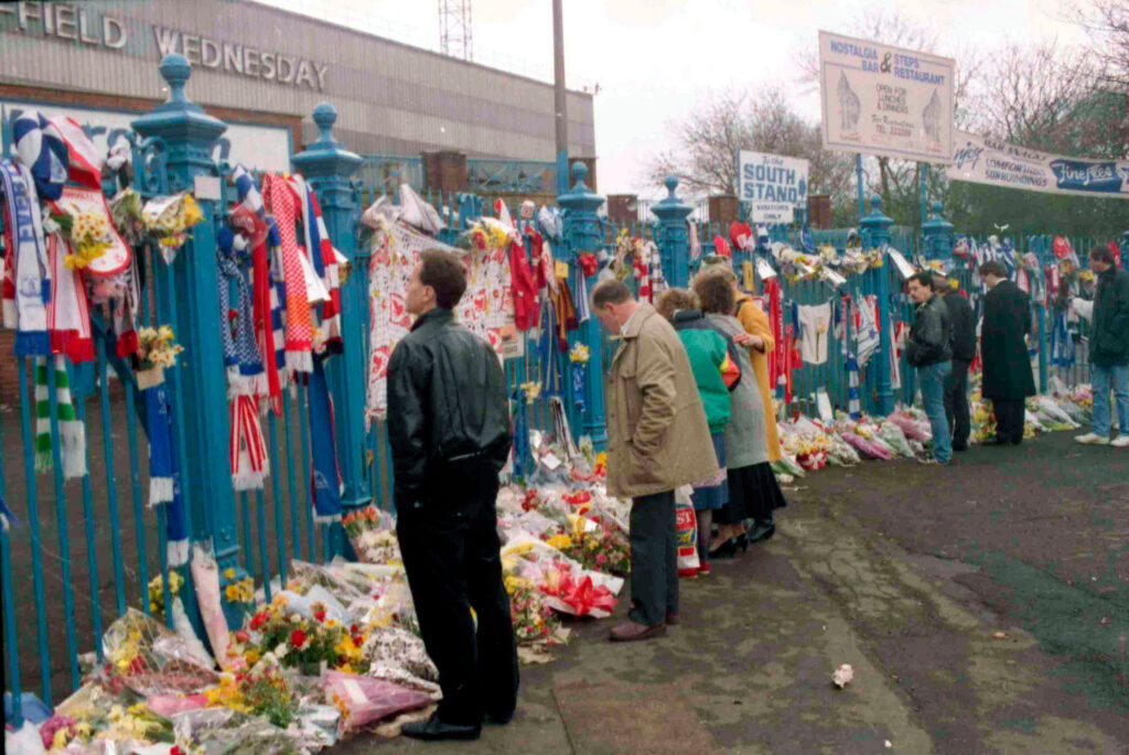 Mourners pay respects at a memorial of scarves and flowers on the gates of Sheffield Wednesday's Hillsborough stadium after the 1989 disaster