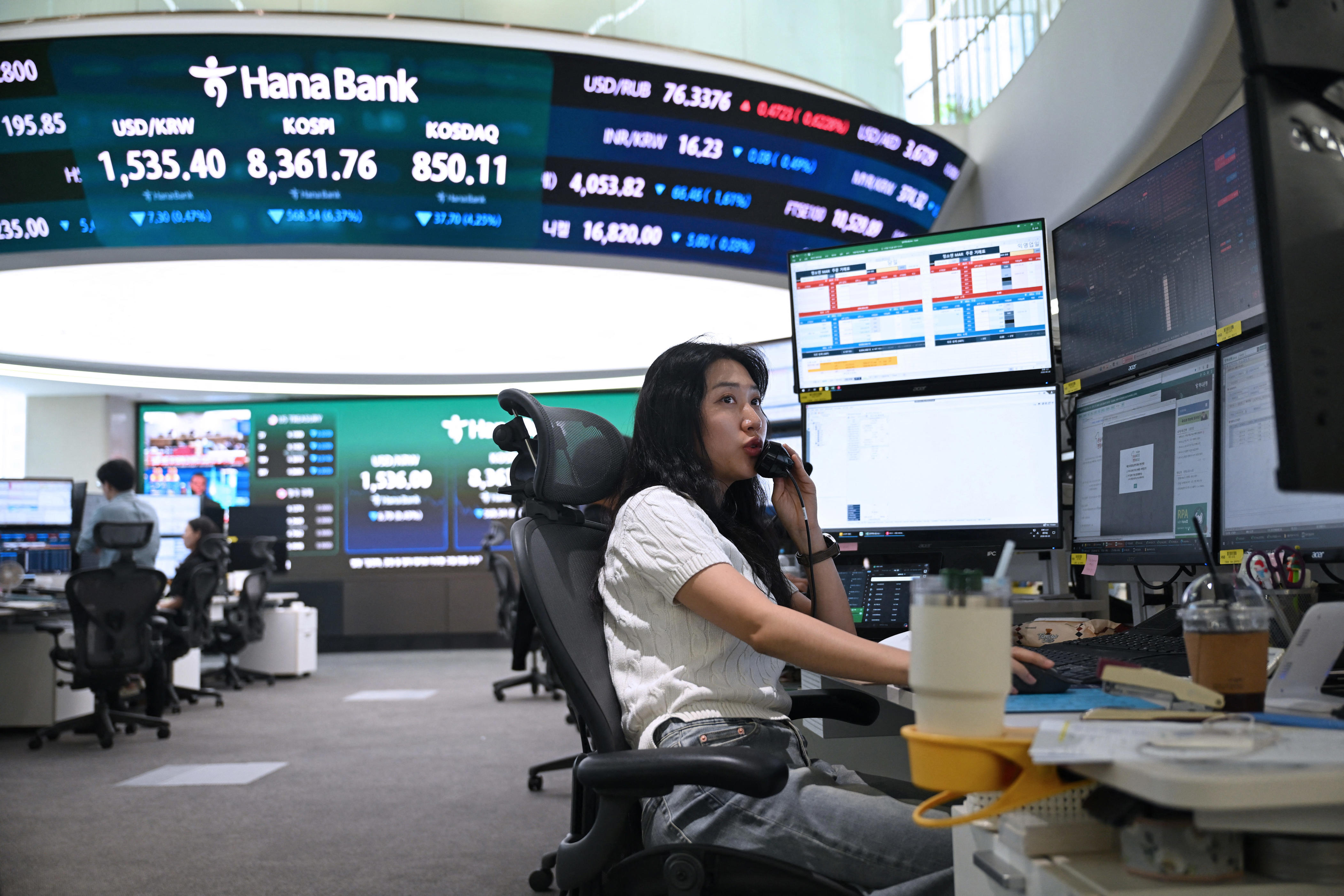 A currency dealer talks on the phone as she monitors exchange rates in a foreign exchange dealing room at the Hana Bank headquarters in Seoul.