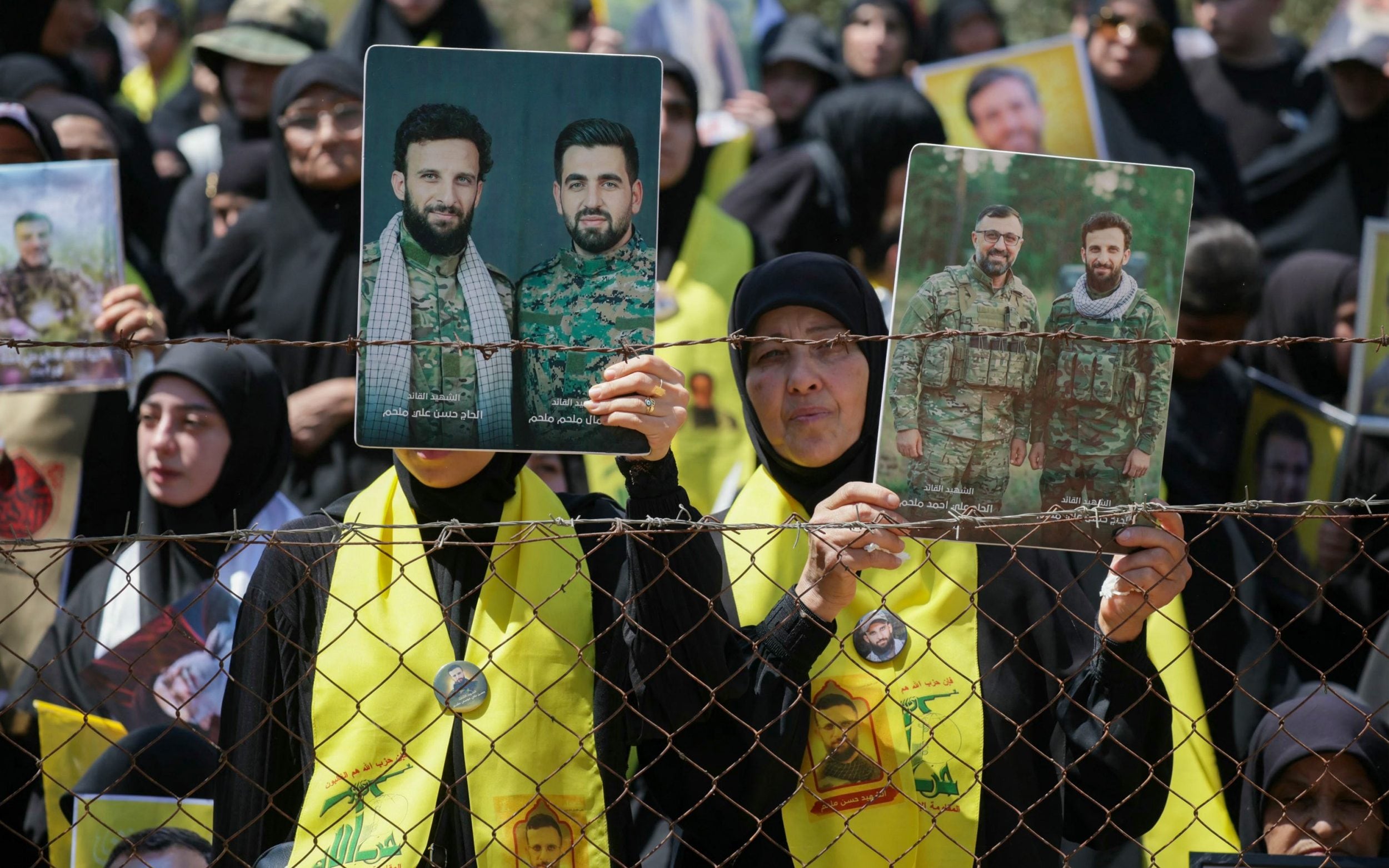 Women hold portraits of Hezbollah fighters who were killed by the Israeli military
