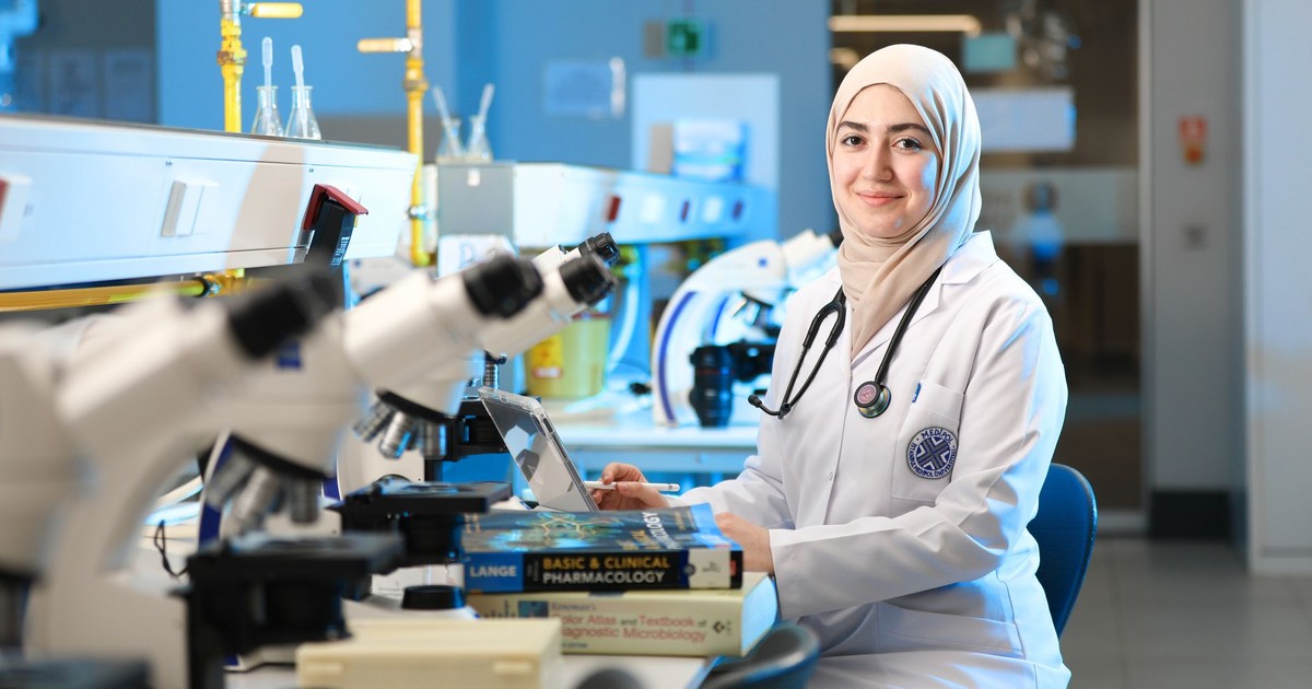 A female scientist in a laboratory setting, conducting research with microscopes and reference books.