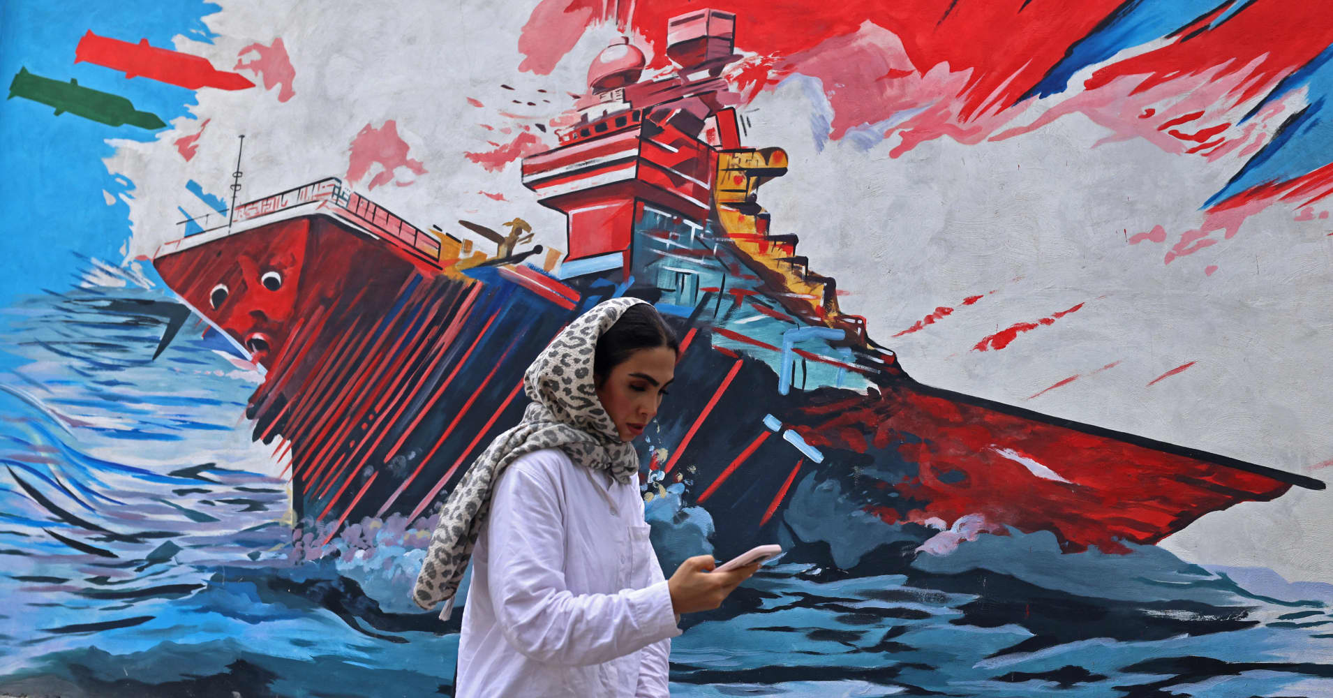 A commuter walks past a wall mural along the street in Tehran on July 21, 2026.