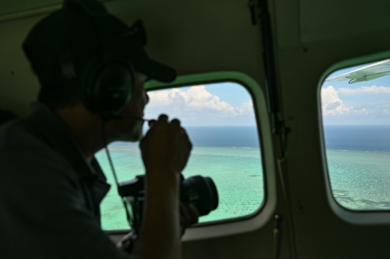 A Philippine Coast Guard personnel talks on a mic as he looks over Scarborough Shoal in the disputed South China Se