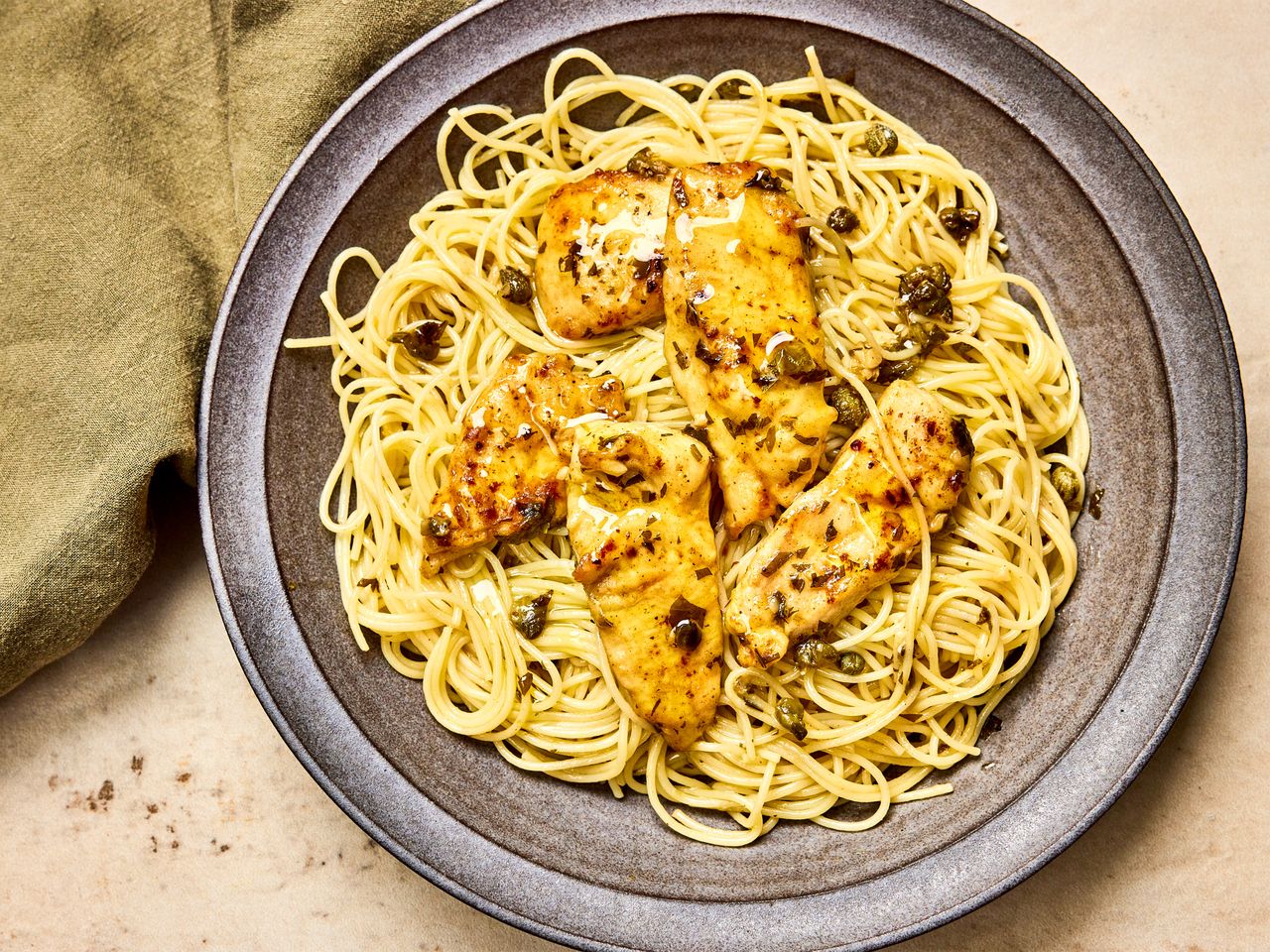 A serving of chicken piccata served over angel hair pasta